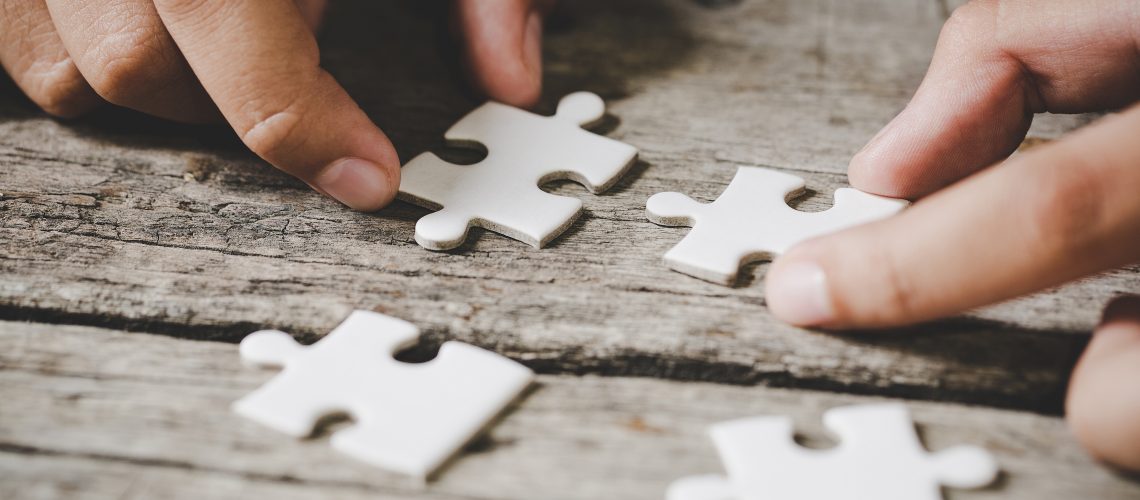 four pieces of white jigsaw on dark wooden table